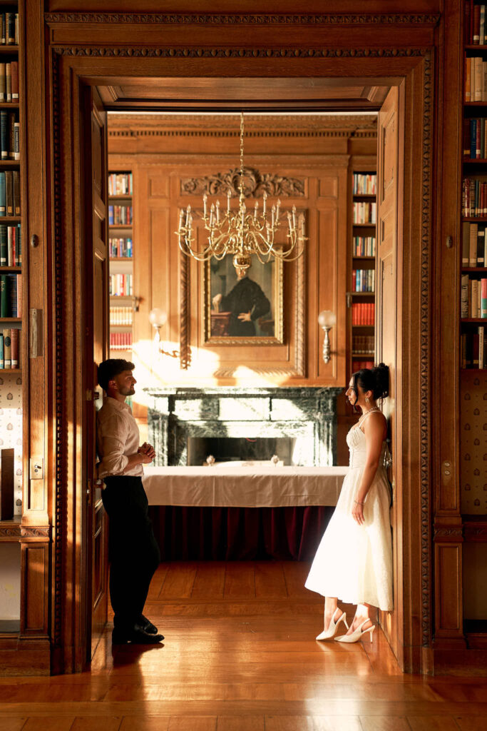 Couple pose by the library room at Aldrich Mansion for vintage inspired engagement photos