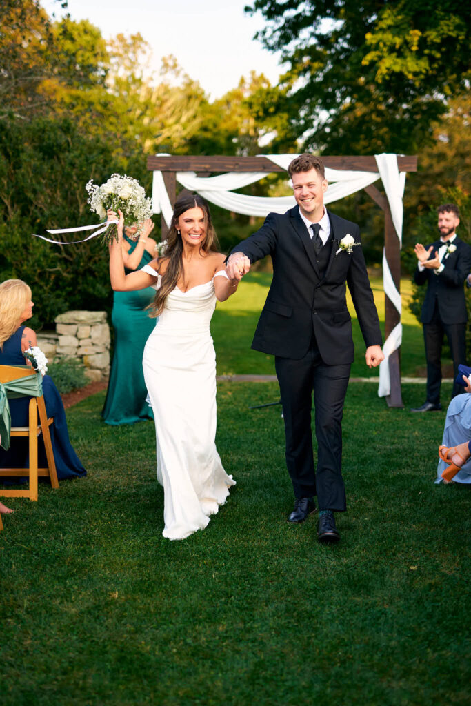Bride and groom smile as they walk down the aisle after their Mount Hope Farm wedding ceremony.