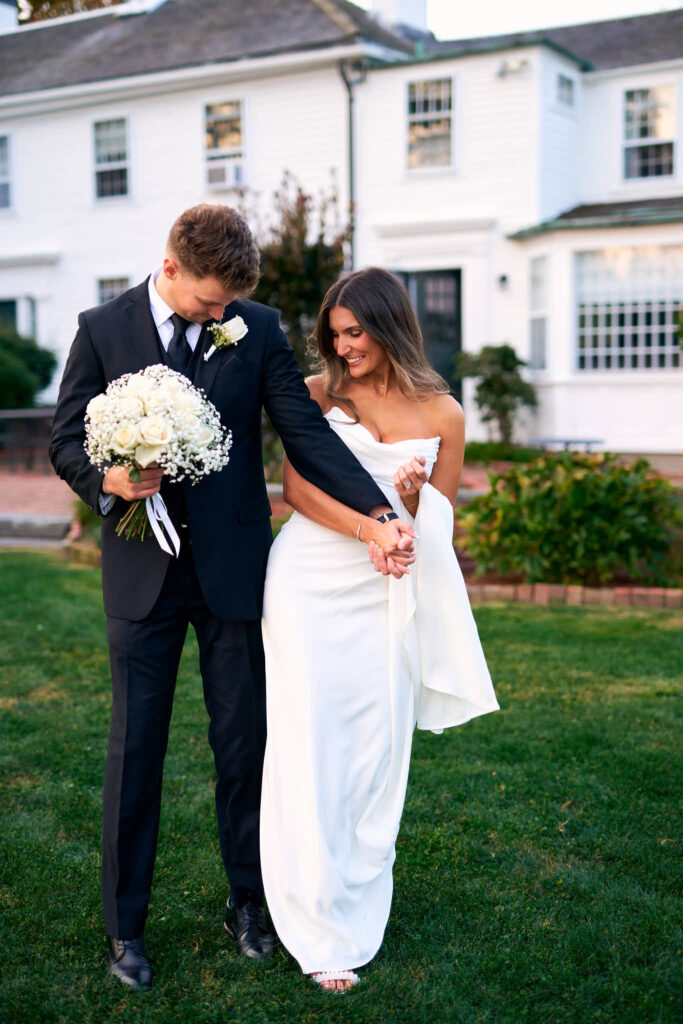 Bride and groom laugh together and hold hands on Mount Hope Farm in Rhode Island.