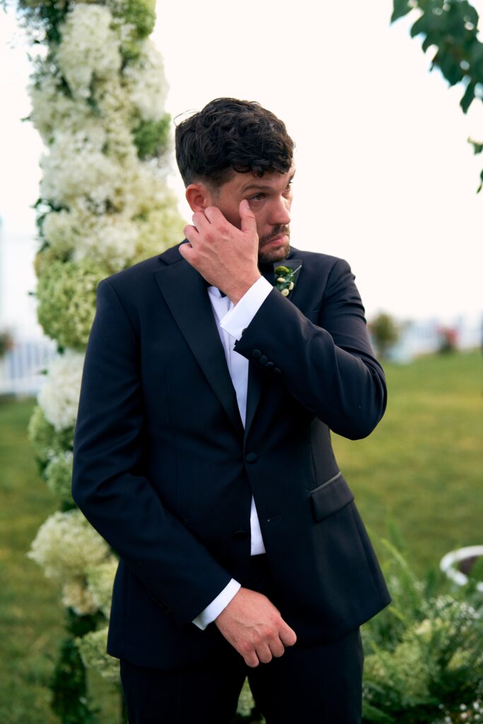 Emotional groom sees his bride walking down the aisle at waterfront wedding in Connecticut